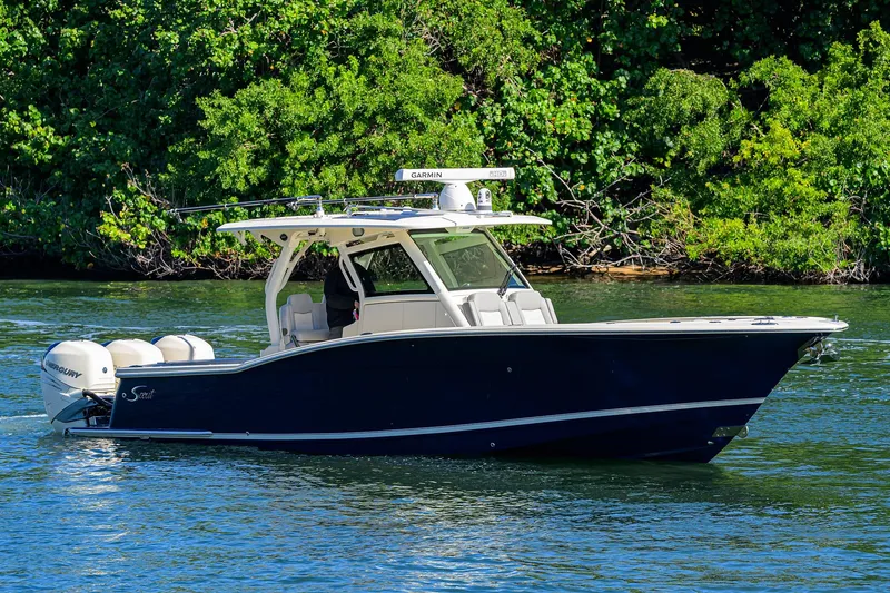 Slide: The Image of 2023 Scout 355 LXF boat on water, surrounded by lush greenery. - 2