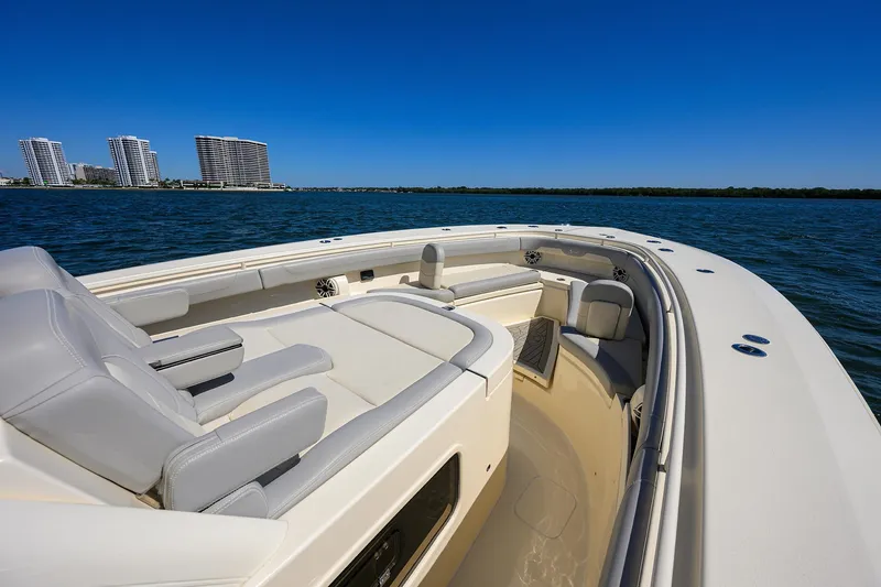 Slide: The Image of 2023 Scout 355 LXF boat on calm water with modern seating and city skyline. - 22