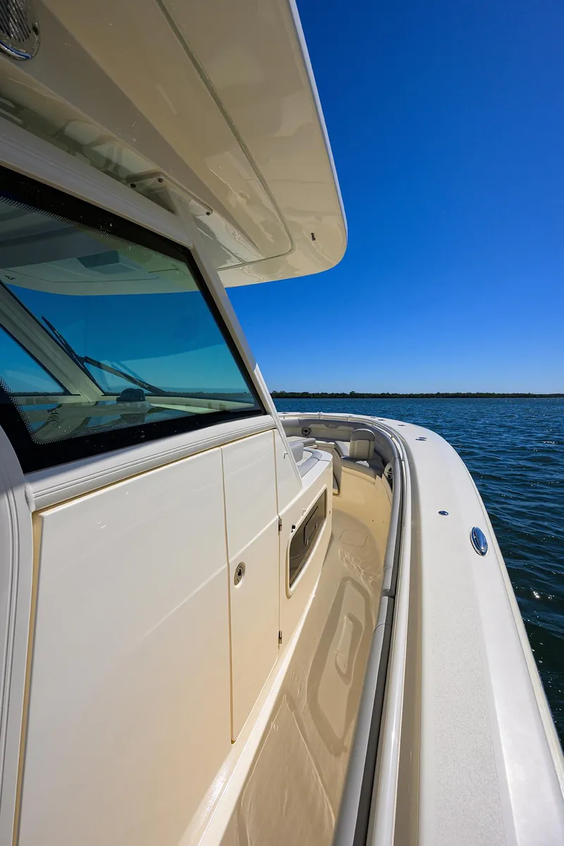 Slide: The Image of 2023 Scout 355 LXF boat on water, showcasing sleek design and clear blue sky. - 29