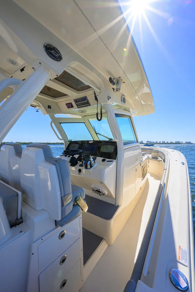 Slide: The Image of 2023 Scout 355 LXF boat interior with helm, seats, and sunny sky. - 44