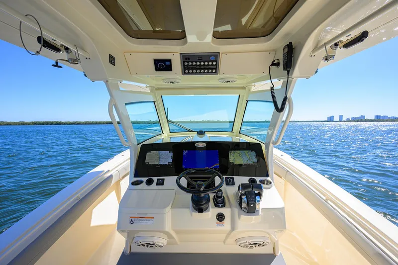 Slide: The Image of 2023 Scout 355 LXF boat helm with modern controls, navigating open water. - 47