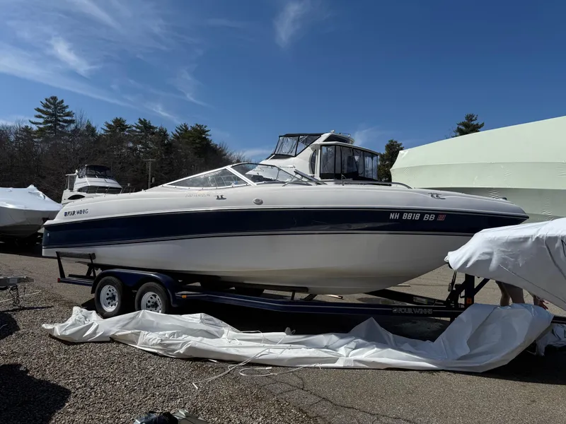Slide: The Image of 1998 Four Winns 240 Horizon boat on trailer, parked outdoors under clear sky. - 0