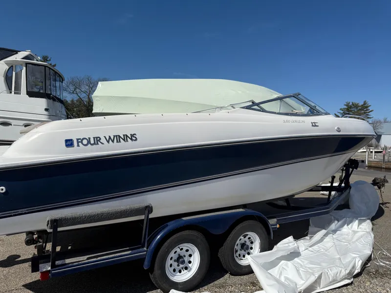 Slide: The Image of 1998 Four Winns 240 Horizon boat on trailer, white and blue design, parked outdoors. - 1