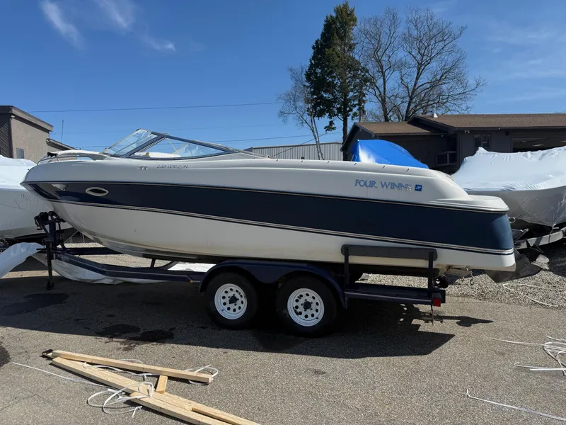 Slide: The Image of 1998 Four Winns 240 Horizon boat on trailer, parked outdoors under clear sky. - 2