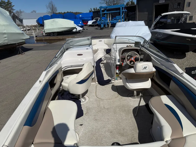 Slide: The Image of 1998 Four Winns 240 Horizon boat interior with seating and steering wheel, parked outdoors. - 4