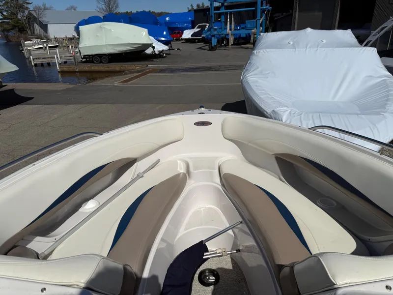 Slide: The Image of 1998 Four Winns 240 Horizon boat interior with white and beige seating, docked near covered boats. - 5