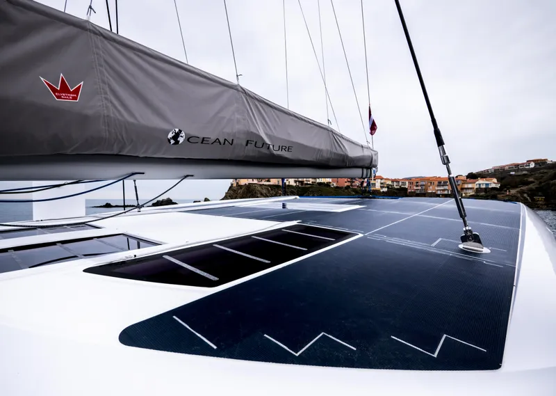 Slide: The Image of 2026 Windelo 50 Adventure catamaran with solar panels and sleek design, docked near coastal town. - 11