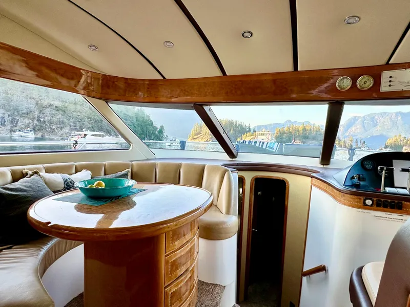 Slide: The Image of Luxurious Prima 5230 yacht interior with round table, plush seating, and scenic marina view. - 10