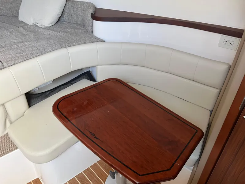 Slide: The Image of 2023 Grady-White Express 330 cabin with cushioned seating and wooden table. - 19