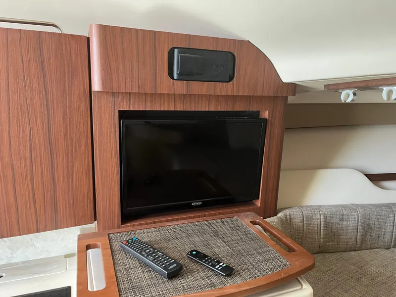 Slide: The Image of 2023 Grady-White Express 330 cabin interior with TV and remote controls. - 21