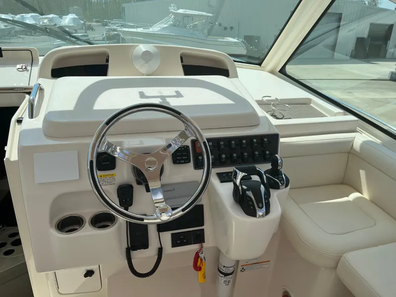 Slide: The Image of 2023 Grady-White Express 330 helm with steering wheel and controls in a sunlit cabin. - 9