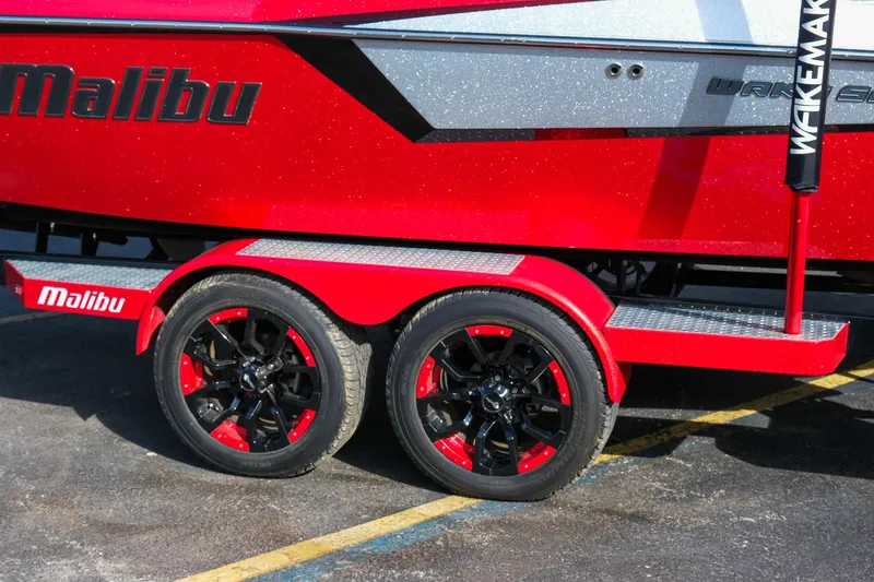 Slide: The Image of Red 2017 Malibu Wakesetter 22 MXZ boat trailer with black and red wheels. - 3