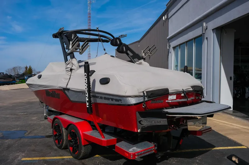 Slide: The Image of 2017 Malibu Wakesetter 22 MXZ boat with cover on red trailer, parked outside. - 34