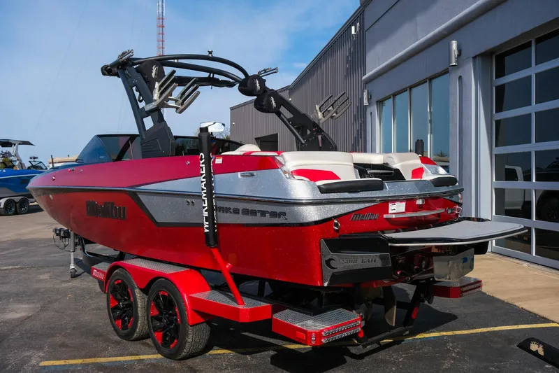 Slide: The Image of 2017 Malibu Wakesetter 22 MXZ boat in vibrant red, parked outside a building. - 4