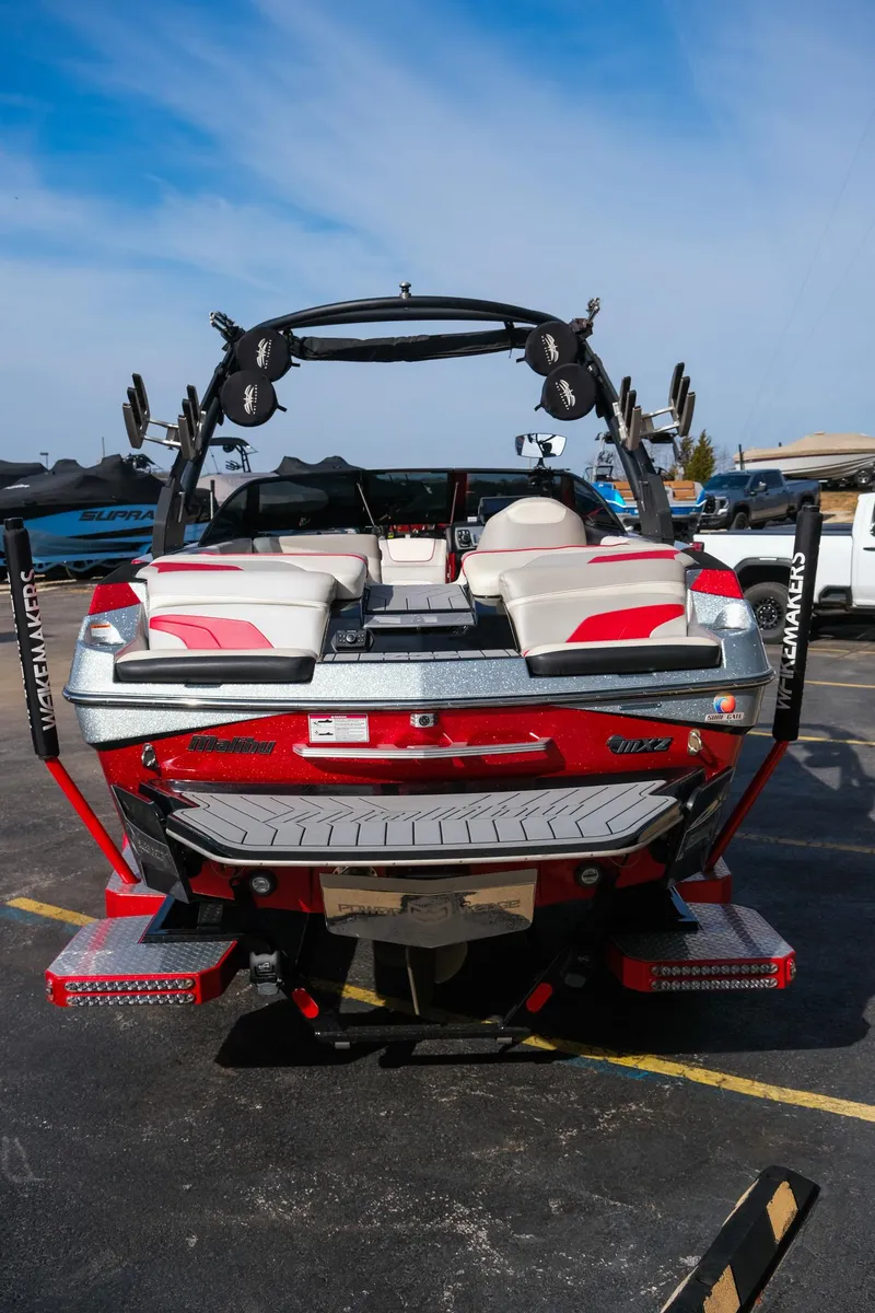 Slide: The Image of 2017 Malibu Wakesetter 22 MXZ boat, rear view, red and white design, parked outdoors. - 5