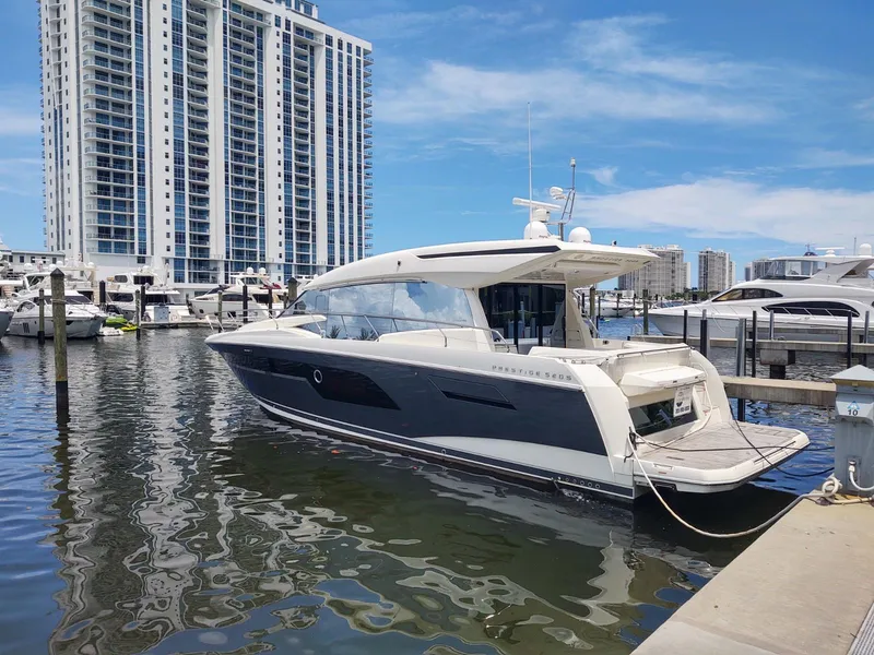 Slide: The Image of 2020 Prestige 520S yacht docked in marina with high-rise buildings in background. - 2
