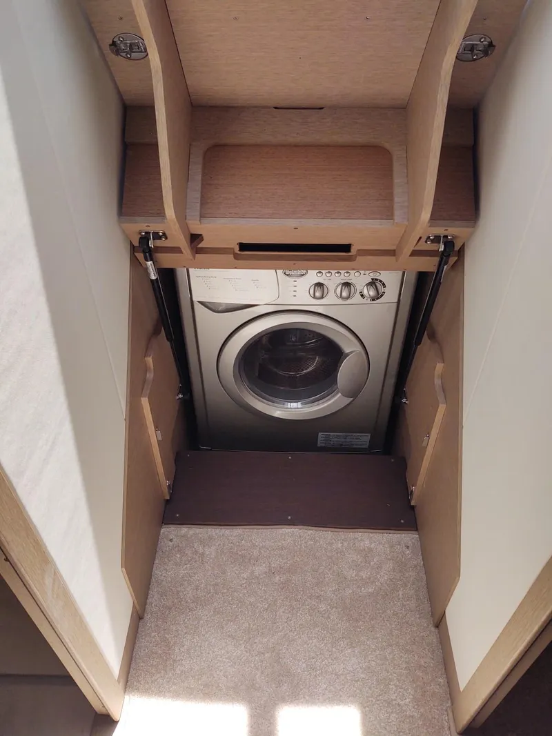 Slide: The Image of Laundry area inside a 2020 Prestige 520S yacht, featuring a compact washing machine. - 37