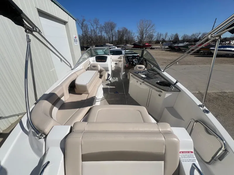 Slide: The Image of 2011 Chaparral 264 Sunesta boat interior with seating and helm, parked outdoors. - 10
