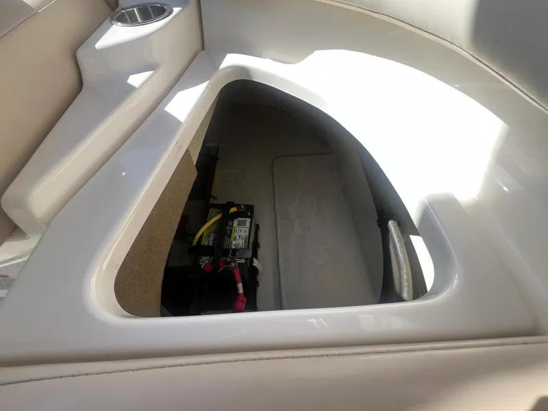 Slide: The Image of Storage compartment in a 2011 Chaparral 264 Sunesta boat, featuring a battery and cup holder. - 30