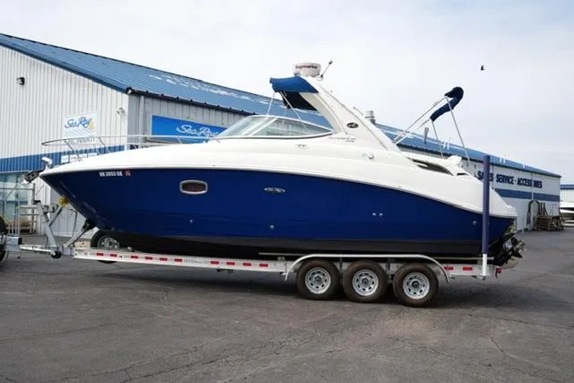 The Image of 2009 Sea Ray 270 Sundancer boat on trailer outside a marine service building. - 1