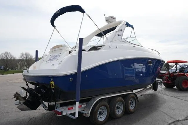 Slide: The Image of 2009 Sea Ray 270 Sundancer boat on trailer, blue and white exterior, parked outdoors. - 5