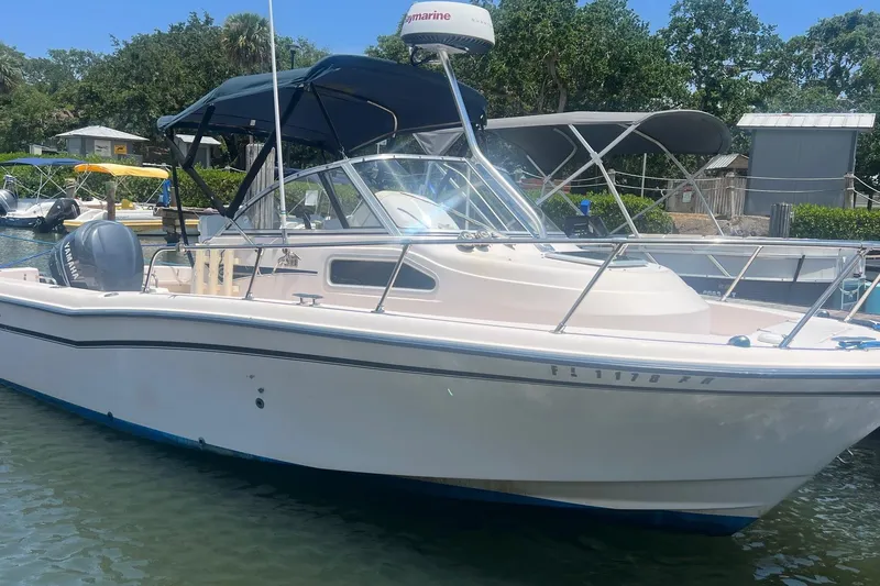 Slide: The Image of 2005 Grady-White Seafarer 226 boat docked in a marina, featuring a blue canopy. - 2