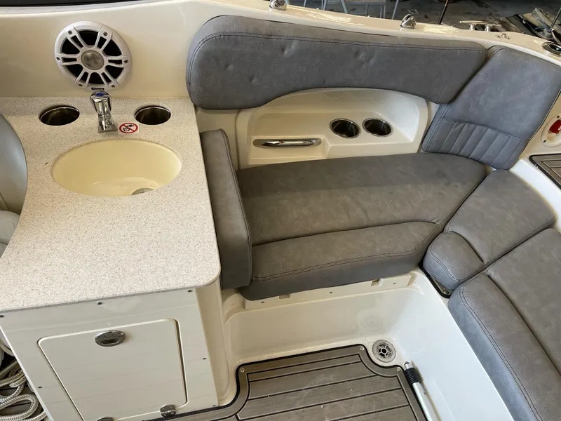 Slide: The Image of 2022 Stingray 231 DC boat interior with gray seating, sink, and cup holders. - 10