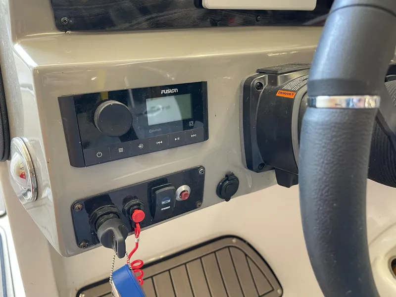 Slide: The Image of Control panel of 2022 Stingray 231 DC boat with steering wheel and audio system. - 13