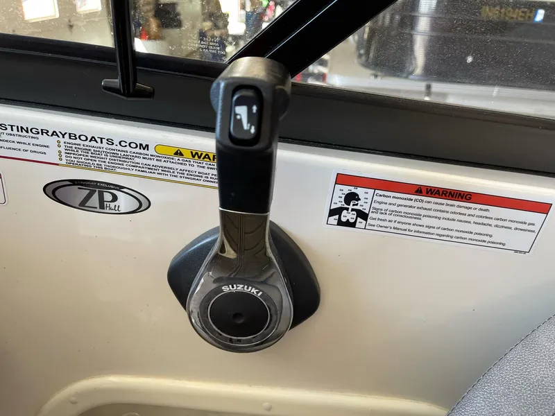 Slide: The Image of Throttle control of a 2022 Stingray 231 DC boat with Suzuki branding and warning labels. - 15