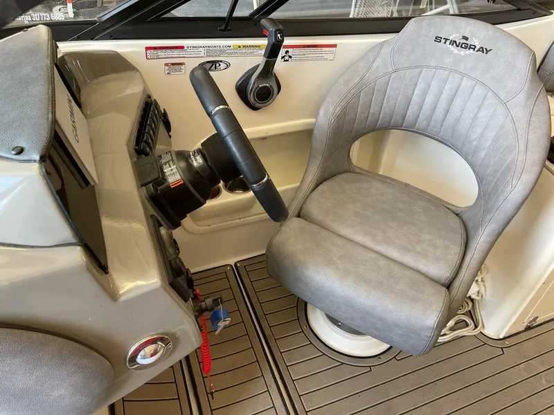 Slide: The Image of 2022 Stingray 231 DC boat interior with steering wheel and gray captain's chair. - 17
