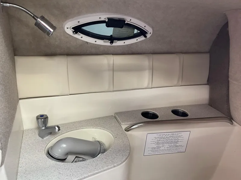 Slide: The Image of 2022 Stingray 231 DC boat interior with sink, faucet, and porthole window. - 18