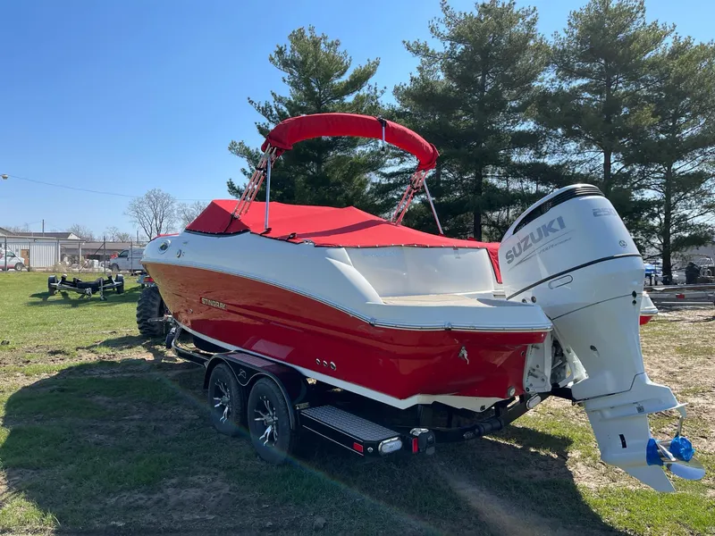 Slide: The Image of 2022 Stingray 231 DC boat with red cover and Suzuki outboard motor on trailer. - 2