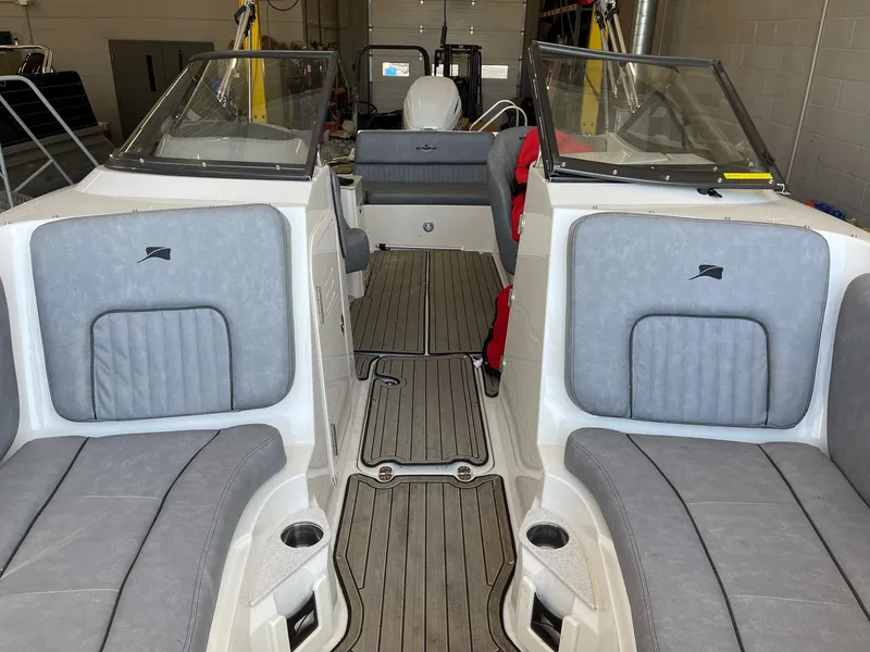 Slide: The Image of 2022 Stingray 231 DC boat interior with gray seating and wood-style flooring. - 22