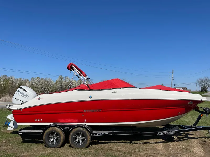 Slide: The Image of 2022 Stingray 231 DC boat in red and white on a trailer, under clear blue sky. - 5