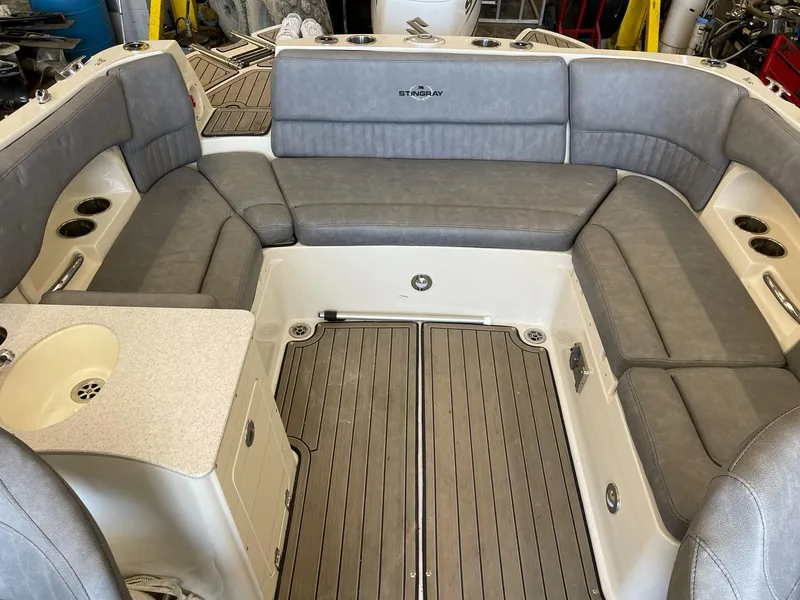 Slide: The Image of 2022 Stingray 231 DC boat interior with gray seating and wood-style flooring. - 8