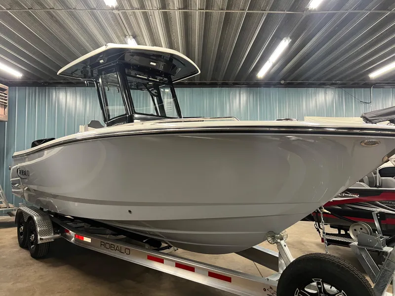 The Image of 2025 Robalo R250 Center Console boat on trailer in indoor storage facility. - 0