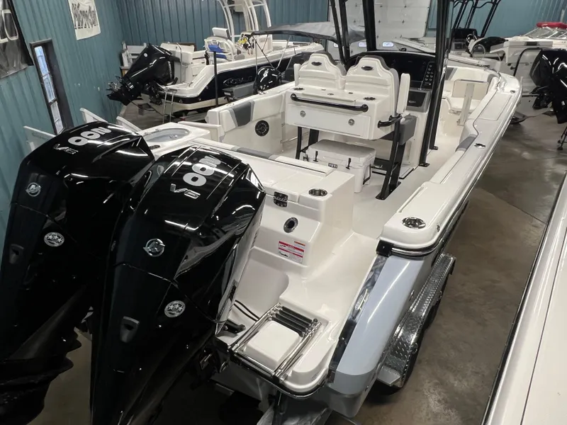 Slide: The Image of 2025 Robalo R250 Center Console boat with dual outboard engines in showroom. - 2