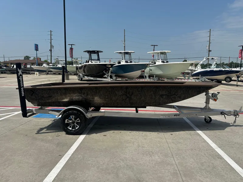 Slide: The Image of 2025 Xpress HD16DBX boat on trailer in parking lot, surrounded by other boats. - 7