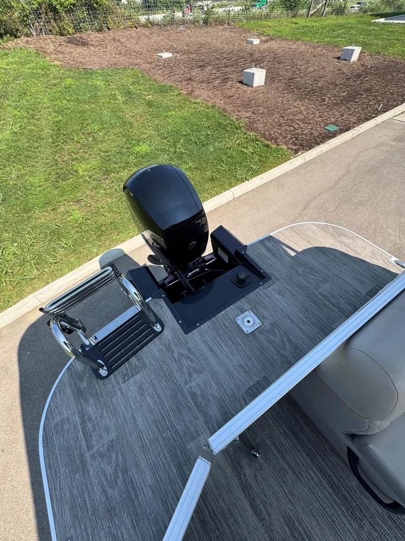 Slide: The Image of 2024 Ranger Reata 223C boat with motor and ladder, parked on pavement. - 3