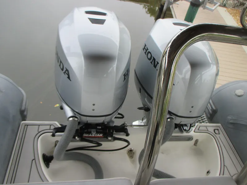 Slide: The Image of Twin Honda outboard motors on a 2021 Zodiac NZO 760 boat, docked by the water. - 5