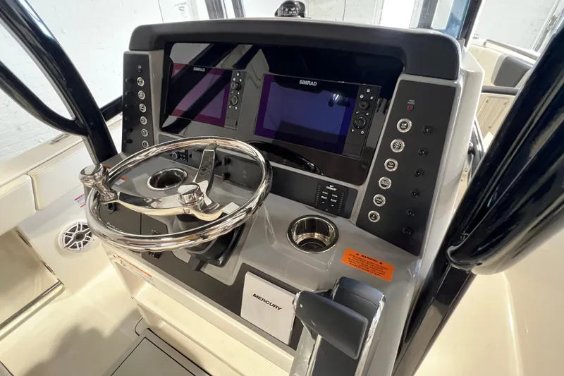 Slide: The Image of 2025 Robalo R230 Center Console boat dashboard with dual Simrad displays and stainless steel steering wheel. - 12