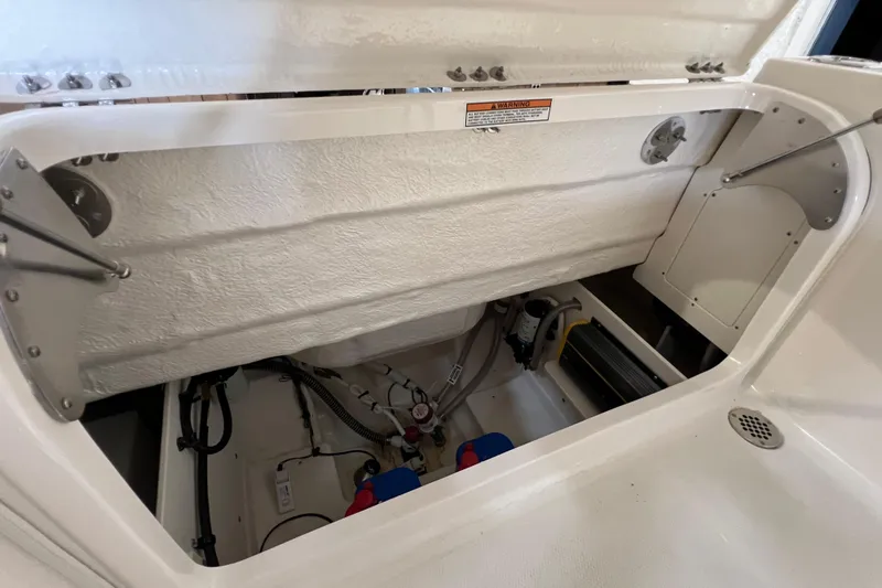 Slide: The Image of 2025 Robalo R230 Center Console storage compartment with open hatch, showcasing interior components. - 13