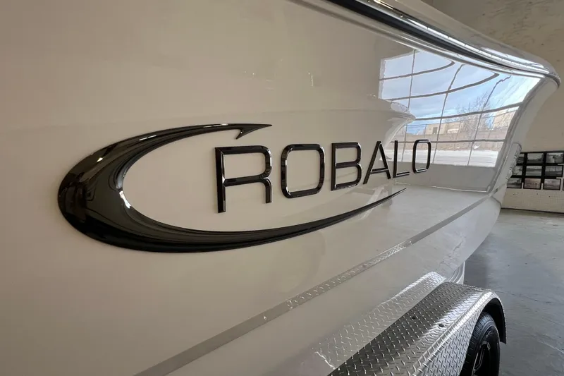 Slide: The Image of 2025 Robalo R230 Center Console boat logo on sleek white hull. - 21