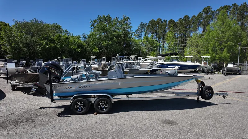 Slide: The Image of 2025 Xpress H22B boat on trailer in outdoor lot, surrounded by trees and other boats. - 10