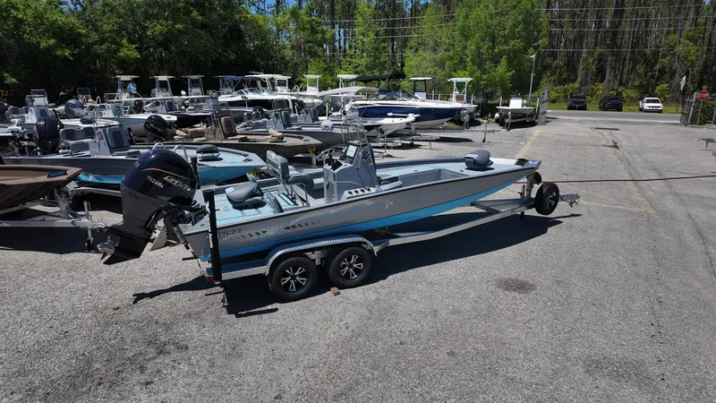 Slide: The Image of 2025 Xpress H22B boat on trailer in parking lot, surrounded by other boats. - 14