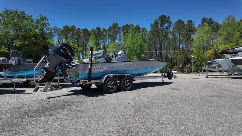 Slide: The Image of 2025 Xpress H22B boat on trailer in outdoor lot, surrounded by trees. - 15