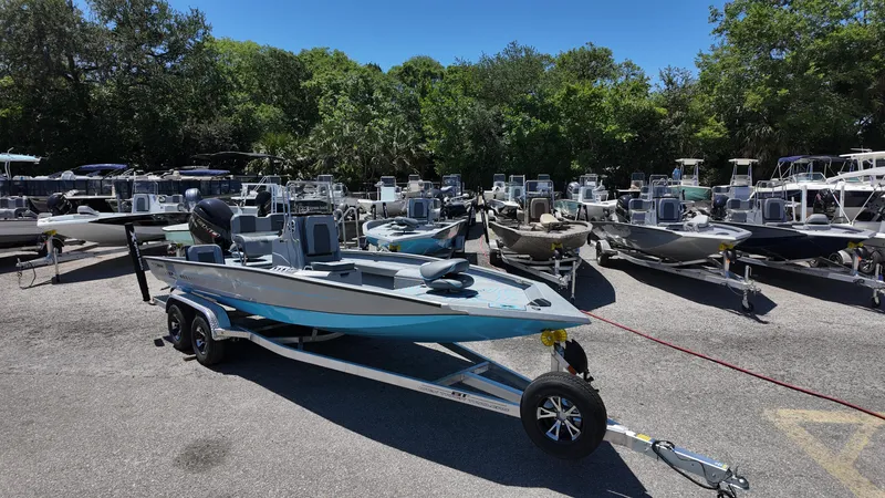 Slide: The Image of 2025 Xpress H22B boat on trailer in outdoor showroom, surrounded by various boats. - 4