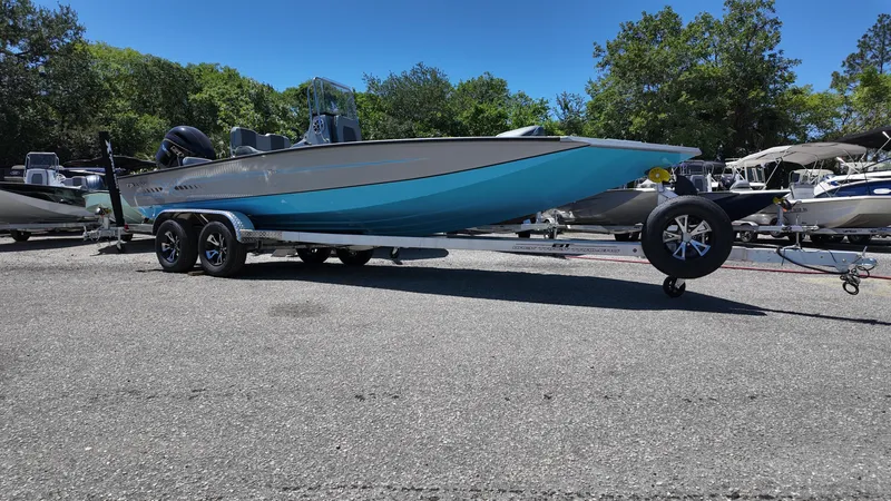 Slide: The Image of 2025 Xpress H22B boat on trailer, parked outdoors, clear sky, surrounded by trees and other boats. - 5