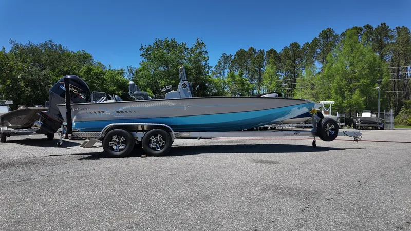 Slide: The Image of 2025 Xpress H22B boat on trailer, parked outdoors, surrounded by trees and clear blue sky. - 9
