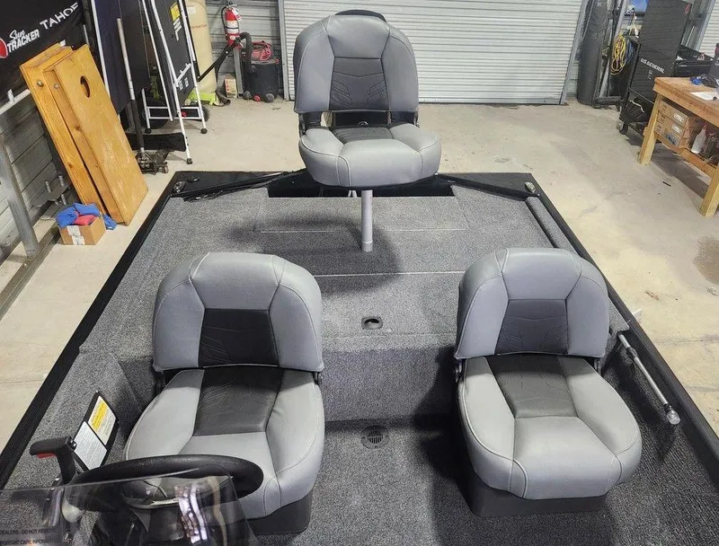 Slide: The Image of 2025 Tracker BASS TRACKER® Classic XL boat interior with three gray seats in a garage. - 8